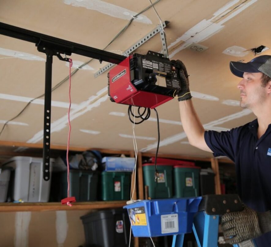 Technician repairing a garage door opener with a toolkit in a residential garage setting